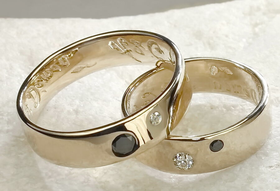 Duo d'alliances classiques Love en or blanc, l'une sertie d'un diamant noir, l'autre de diamants.
