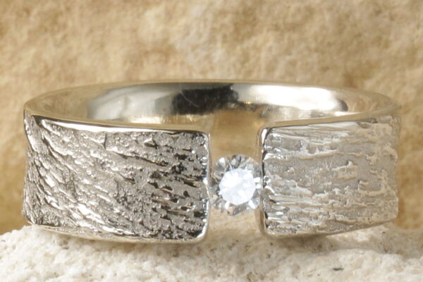 Alliance Silence avec un diamant central suspendu en largeur 6 mm, bords droits sans bordures, en or blanc rhodié.